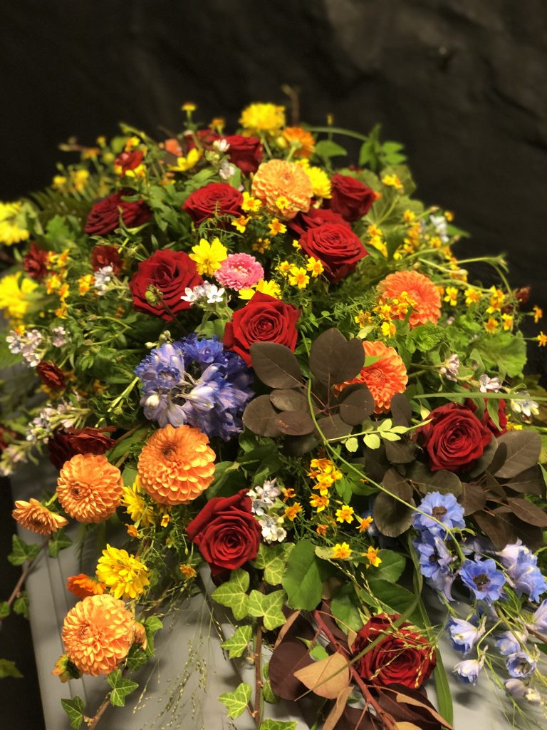 Blommor i olika färger ovanpå kista