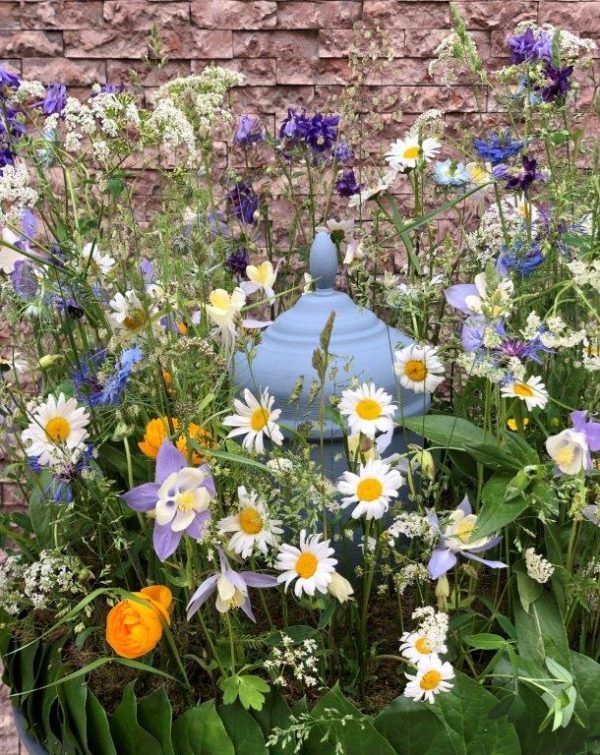 Krans med blommor mot stenvägg med urna i mitten