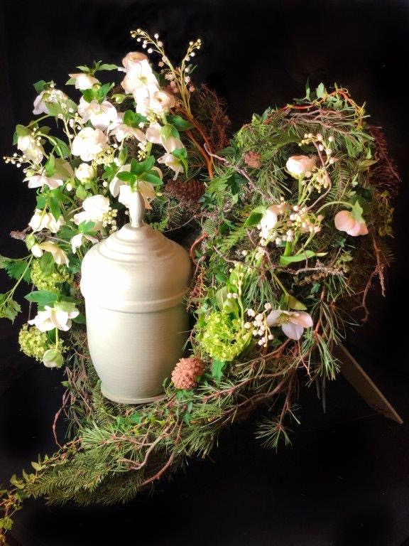 Vita blommor bakom en ljus urna