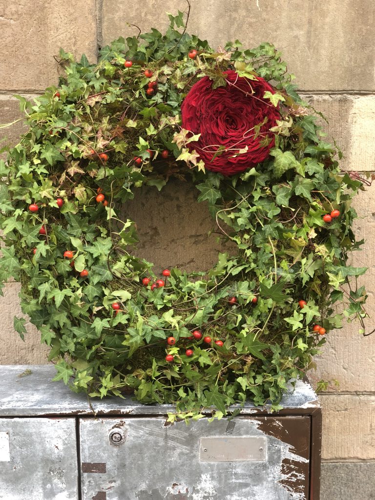 Grön krans med stor röd blomma