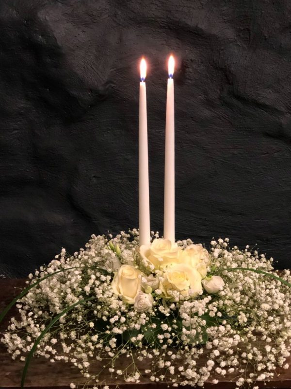 Vita blommor vid två vita tända ljus