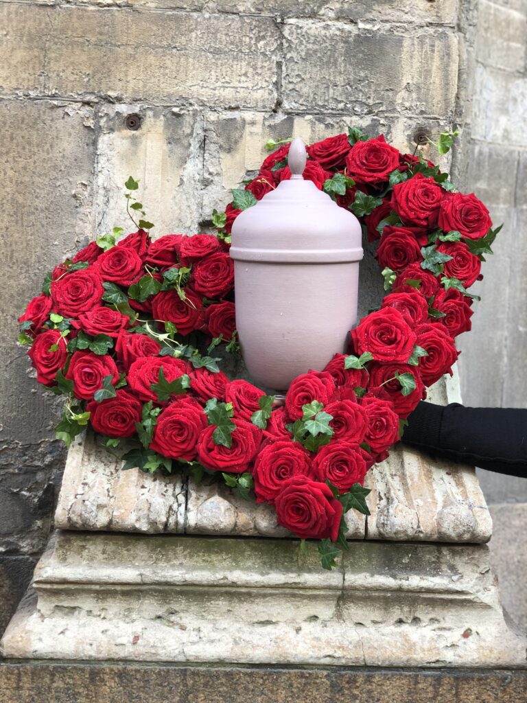 Röda rosor format som hjärta med urna i mitten